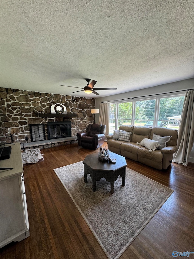 living room featuring a textured ceiling, a fireplace, ceiling fan, and dark wood-type flooring