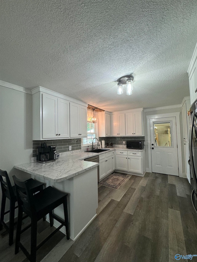 kitchen featuring white cabinets, kitchen peninsula, a textured ceiling, dark hardwood / wood-style floors, and decorative backsplash