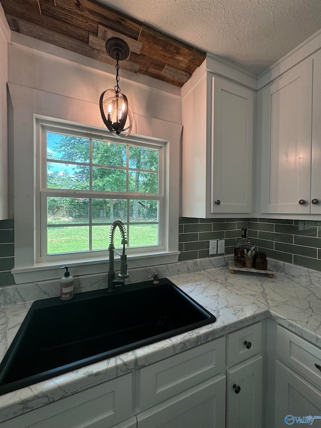 kitchen with a healthy amount of sunlight, sink, and white cabinets