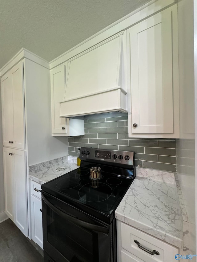 kitchen with light stone countertops, white cabinetry, electric stove, and tasteful backsplash