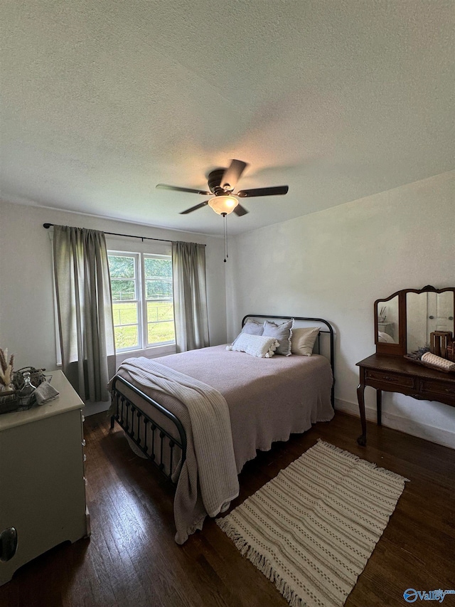 bedroom featuring ceiling fan, dark hardwood / wood-style floors, and a textured ceiling