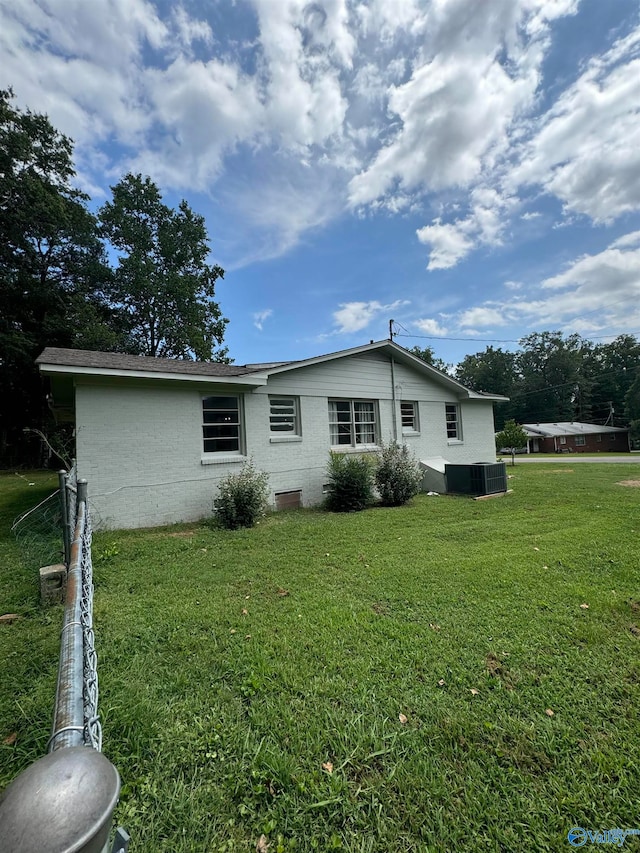 back of property featuring a lawn and central air condition unit