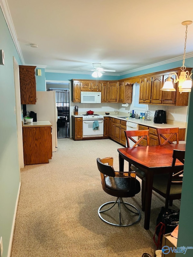 kitchen featuring pendant lighting, white appliances, light countertops, brown cabinets, and crown molding