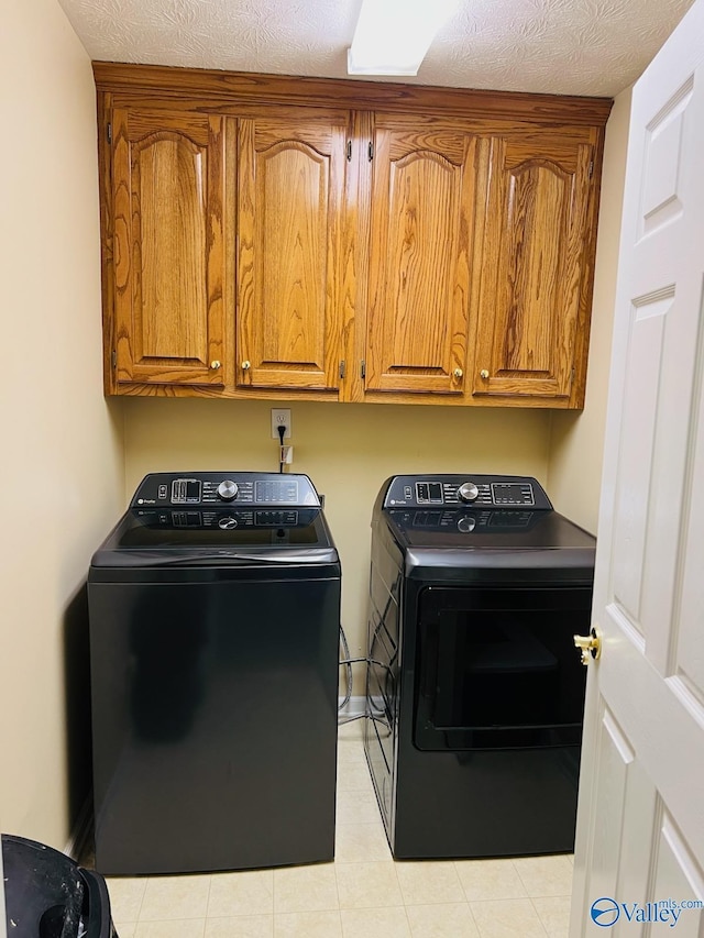 laundry room with a textured ceiling, washing machine and dryer, and cabinet space