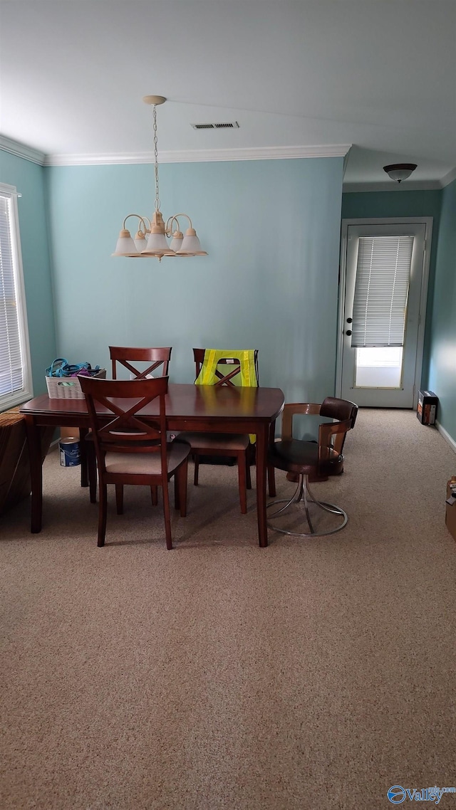 dining area featuring carpet, visible vents, crown molding, and an inviting chandelier