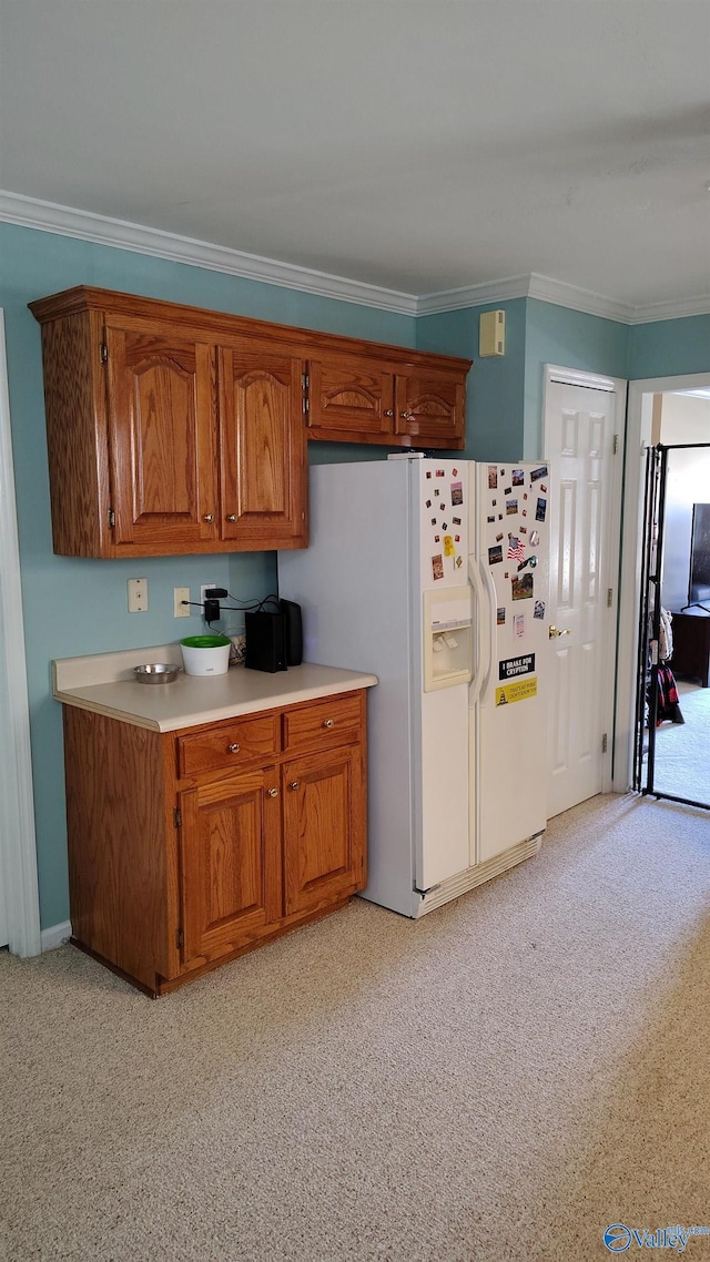 kitchen featuring white fridge with ice dispenser, ornamental molding, light countertops, and brown cabinets