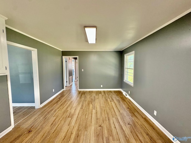 spare room with ornamental molding and light hardwood / wood-style flooring