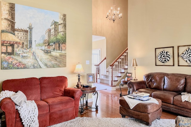 living area featuring baseboards, a towering ceiling, wood finished floors, stairs, and a notable chandelier