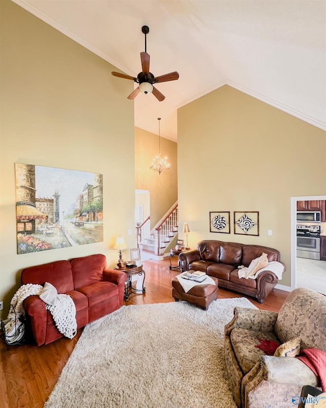 living area featuring ornamental molding, wood finished floors, stairs, high vaulted ceiling, and ceiling fan with notable chandelier