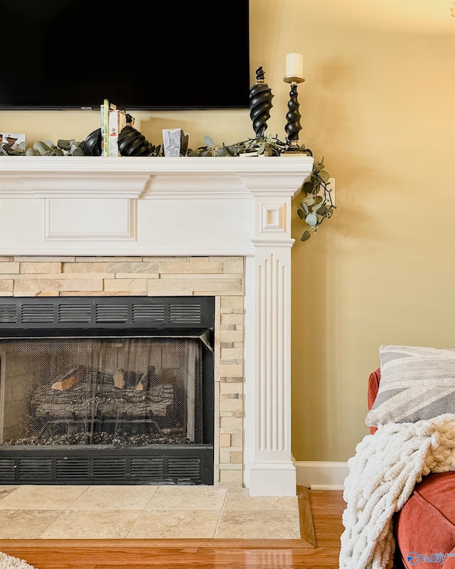 details featuring ornate columns, a fireplace with flush hearth, baseboards, and wood finished floors