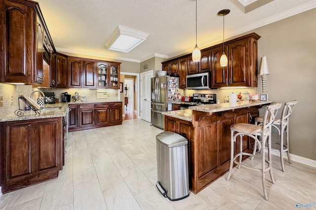 kitchen with light stone counters, a breakfast bar, stainless steel appliances, a sink, and a peninsula