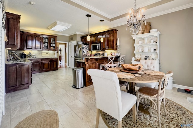 dining space featuring baseboards, crown molding, a tray ceiling, and a notable chandelier