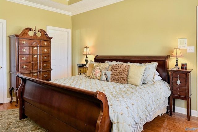 bedroom featuring ornamental molding, wood finished floors, and baseboards