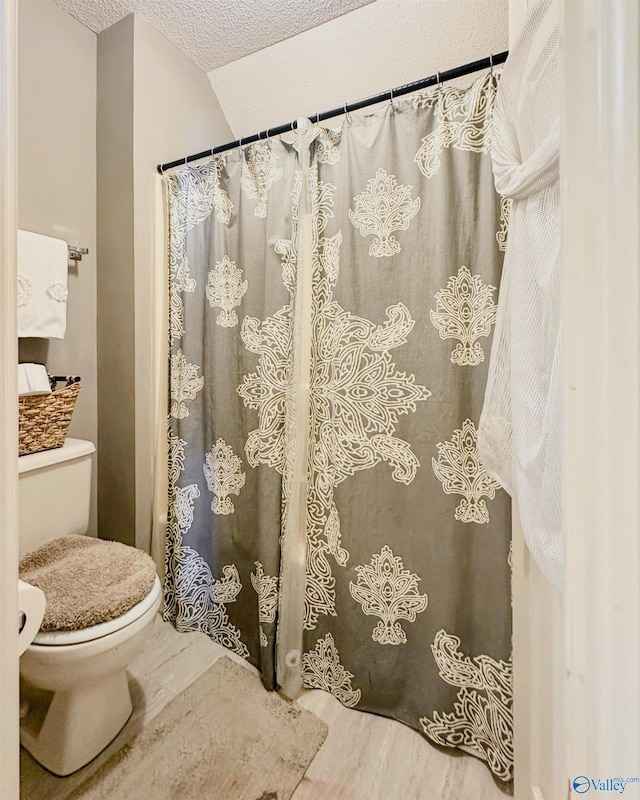 full bath featuring a textured ceiling and toilet