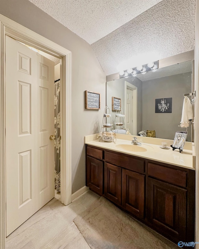 bathroom featuring lofted ceiling, a textured ceiling, and vanity