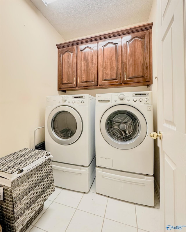 clothes washing area with cabinet space, independent washer and dryer, a textured ceiling, and light tile patterned flooring