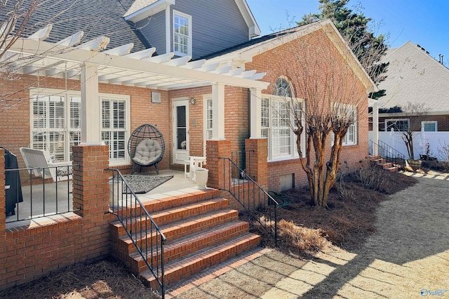 entrance to property with a shingled roof and brick siding