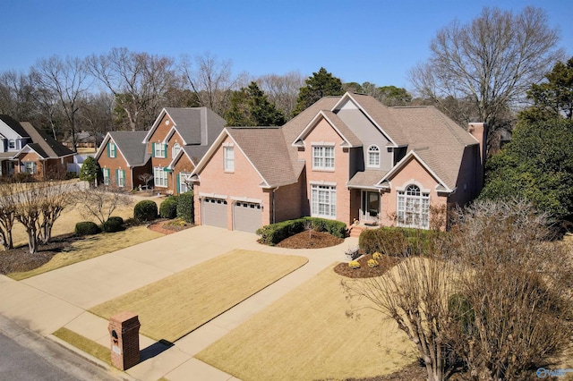 traditional-style home featuring an attached garage, a residential view, concrete driveway, and brick siding