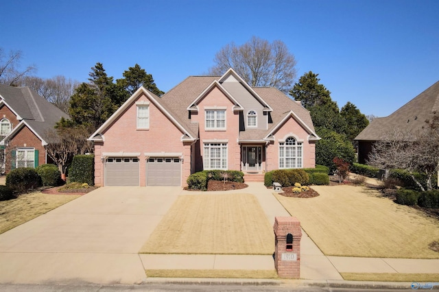 traditional-style house featuring an attached garage, concrete driveway, and brick siding