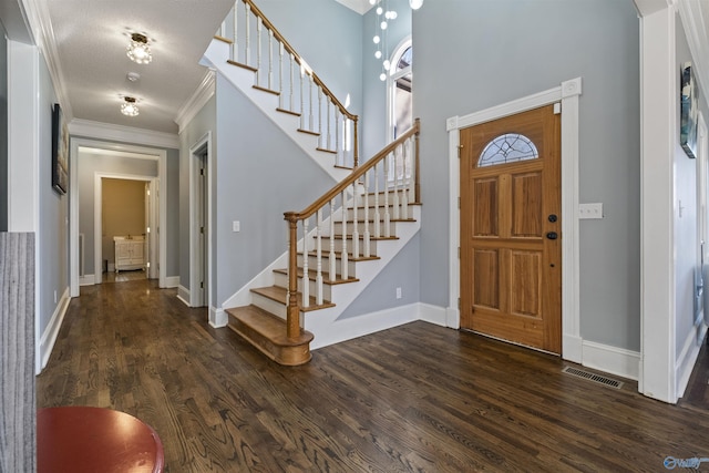 foyer featuring dark hardwood / wood-style flooring, crown molding, and a textured ceiling