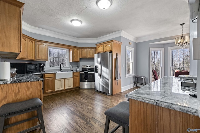 kitchen featuring dark stone countertops, an inviting chandelier, stainless steel appliances, and pendant lighting