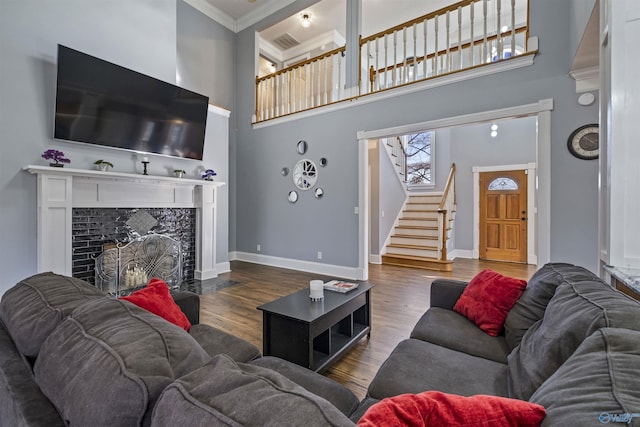 living room with a high ceiling, a high end fireplace, ornamental molding, and dark hardwood / wood-style floors