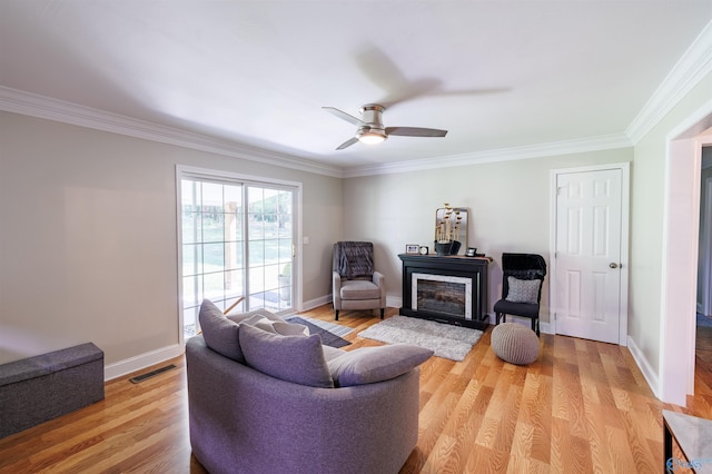 sitting room featuring baseboards, visible vents, a ceiling fan, crown molding, and light wood-type flooring