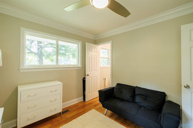 sitting room with ornamental molding, visible vents, light wood-style flooring, and baseboards
