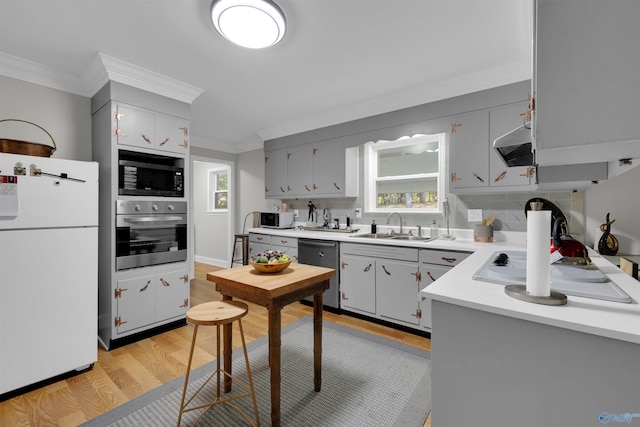 kitchen featuring tasteful backsplash, ornamental molding, stainless steel appliances, light countertops, and a sink