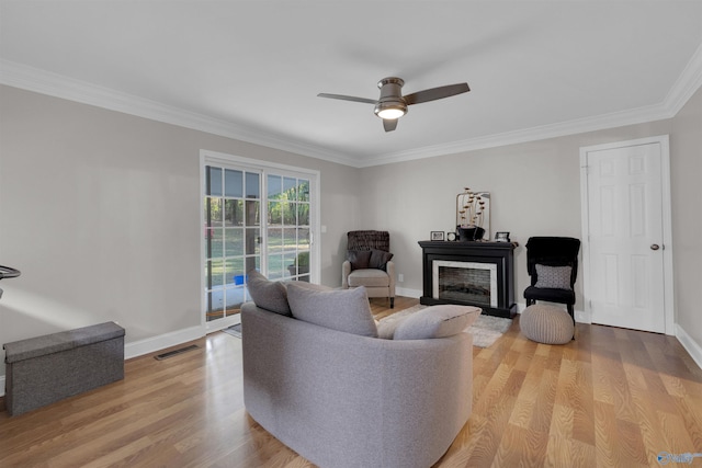 living room featuring light wood-style flooring, crown molding, visible vents, and baseboards