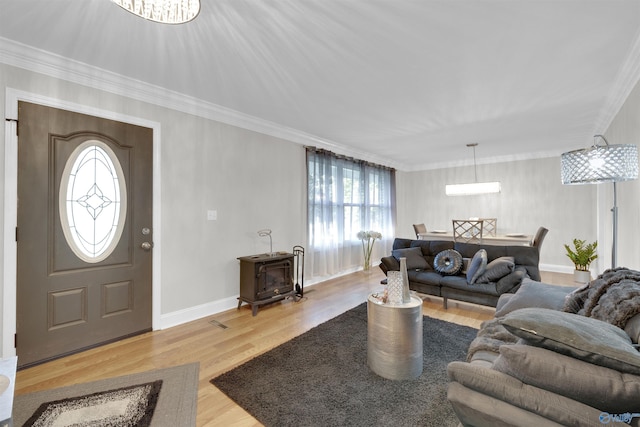 living area with a wood stove, baseboards, ornamental molding, and wood finished floors