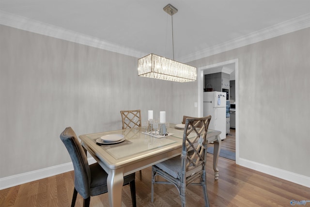 dining room featuring light wood finished floors, baseboards, ornamental molding, and an inviting chandelier