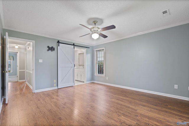 2303 Chatam Ave, Decatur, AL 35603 - unfurnished bedroom with crown molding, wood finished floors, a textured ceiling, a barn door, and baseboards