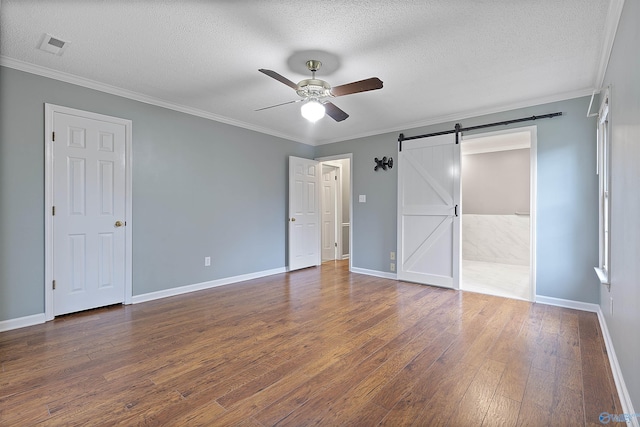 2303 Chatam Ave, Decatur, AL 35603 - unfurnished bedroom featuring dark wood-style flooring, a textured ceiling, baseboards, a barn door, and ornamental molding