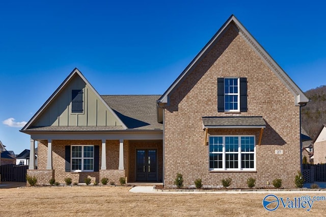 view of front of home featuring a front yard, french doors, and covered porch