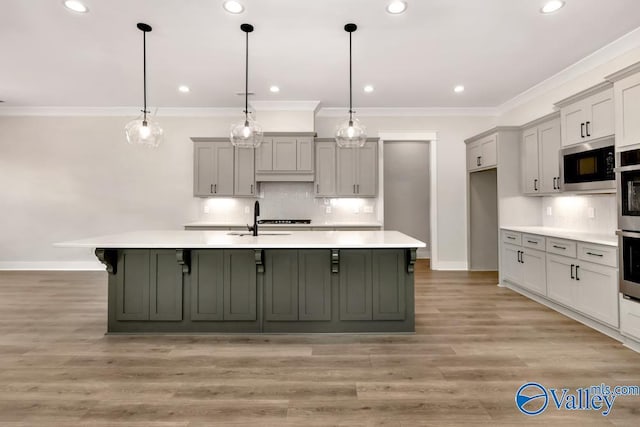 kitchen featuring built in microwave, sink, decorative light fixtures, and gray cabinetry