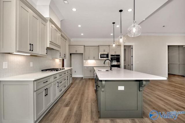 kitchen featuring appliances with stainless steel finishes, sink, hanging light fixtures, ornamental molding, and a spacious island