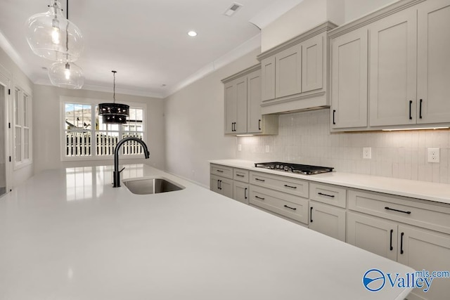 kitchen featuring pendant lighting, sink, ornamental molding, decorative backsplash, and stainless steel gas stovetop