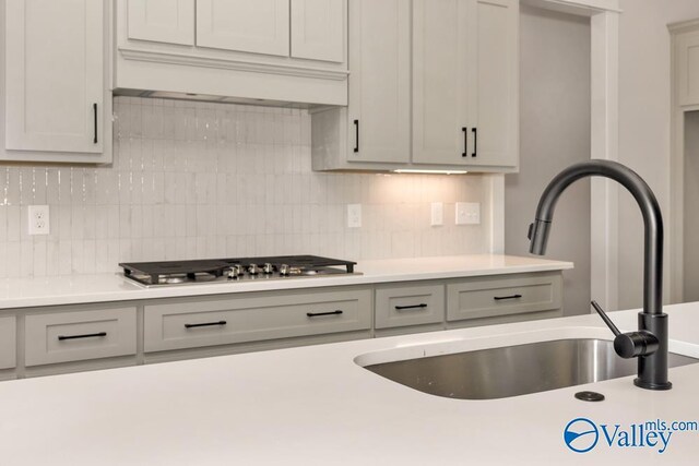 kitchen with tasteful backsplash, sink, and stainless steel gas stovetop