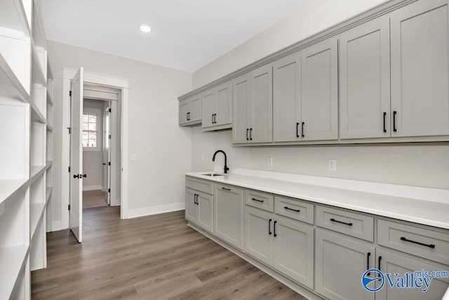 kitchen with sink, hardwood / wood-style floors, and gray cabinetry