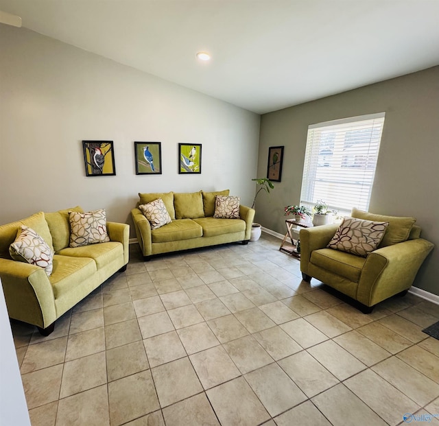 living room with vaulted ceiling, baseboards, and light tile patterned floors