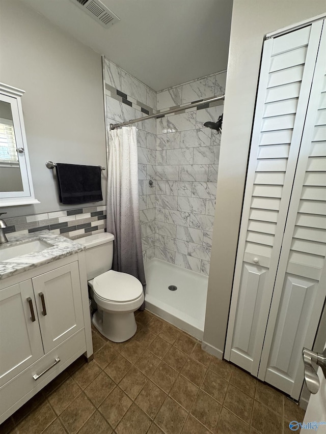 bathroom with toilet, vanity, a shower stall, and visible vents