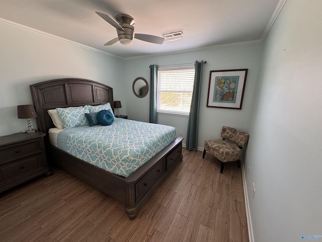 bedroom featuring baseboards, wood finished floors, visible vents, and crown molding