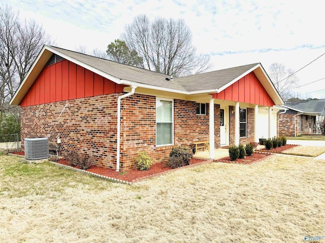 view of front of house featuring brick siding, board and batten siding, a front yard, and central air condition unit