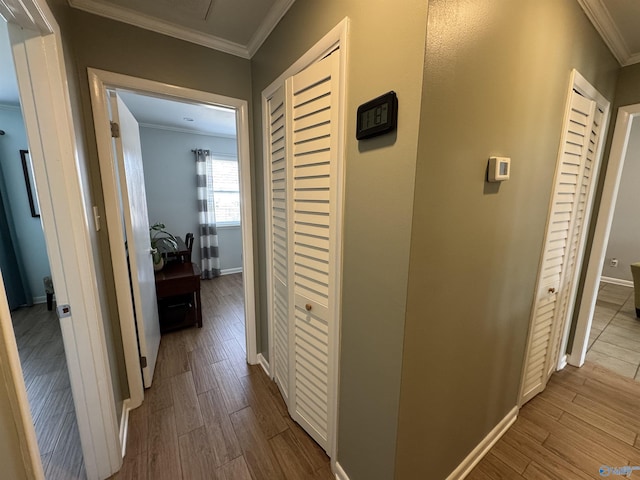 corridor featuring dark wood-type flooring, crown molding, and baseboards