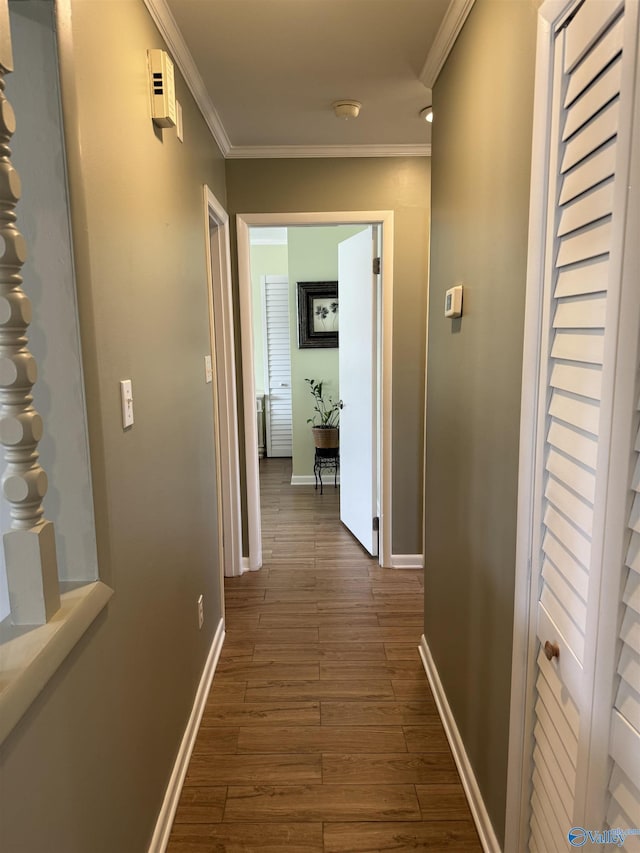 corridor featuring baseboards, ornamental molding, and dark wood-style flooring