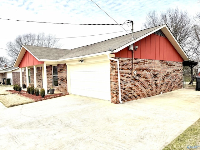 view of property exterior with driveway, an attached garage, board and batten siding, and brick siding