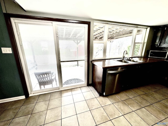 kitchen featuring baseboards, a sink, stainless steel dishwasher, and light tile patterned floors