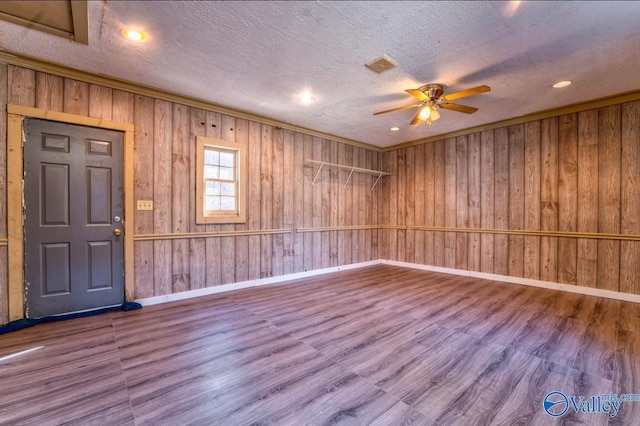 interior space featuring hardwood / wood-style flooring, ceiling fan, and wood walls