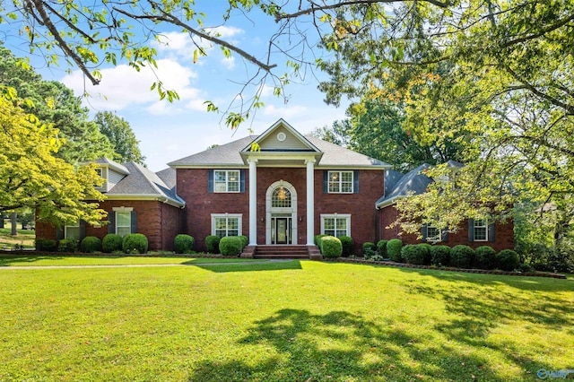 neoclassical / greek revival house with a front yard and brick siding